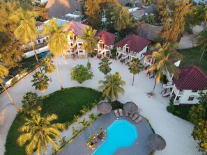 A resort with multiple buildings, a swimming pool, and palm trees. - Smiles Beach Hotel (Nungwi)