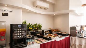 Disposição de buffet com máquina de café, limões frescos e diversas opções de comida.