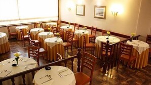 Un comedor con mesas redondas, sillas e imágenes enmarcadas en las paredes.
