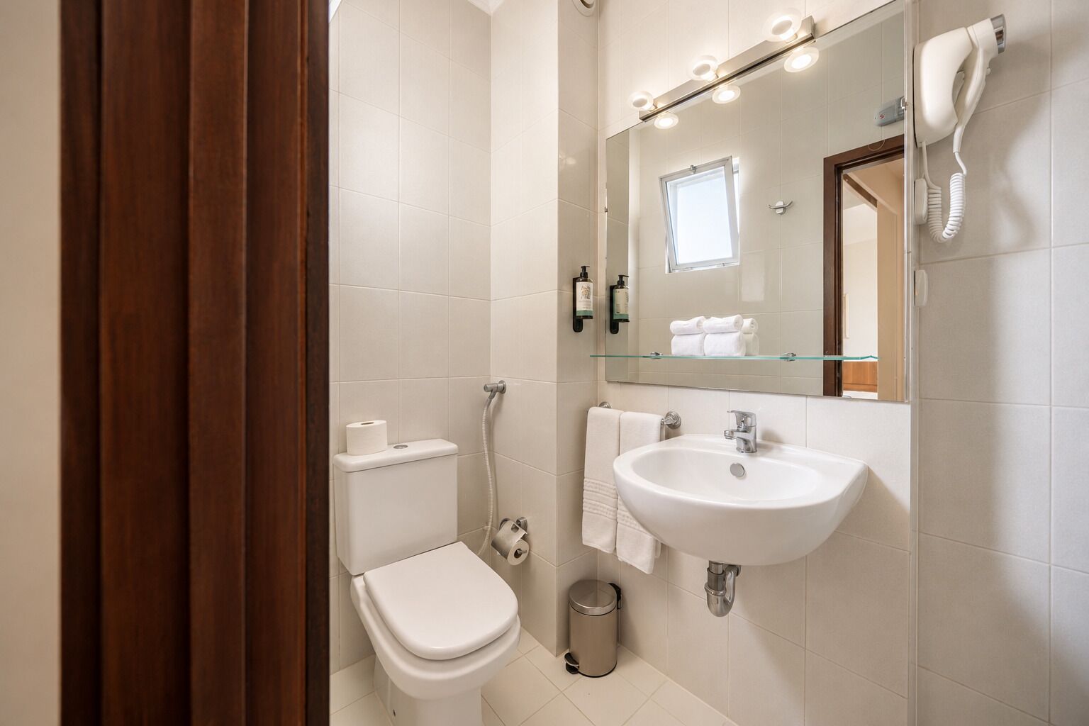 A bathroom with a toilet, sink, and mirror.