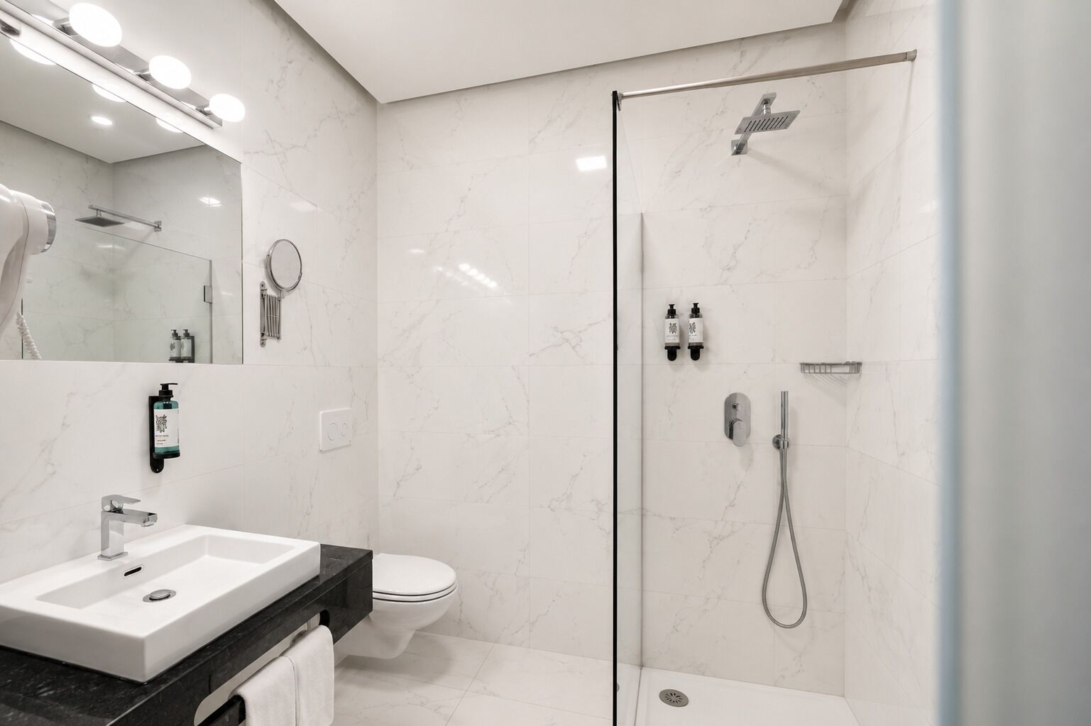 Un baño moderno con ducha envuelta en vidrio, un lavabo blanco y un inodoro.