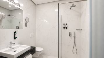 Un baño moderno con ducha envuelta en vidrio, un lavabo blanco y un inodoro.