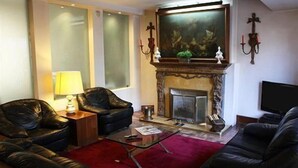Una sala de estar con chimenea, sofás de cuero, una mesa de centro de vidrio y una alfombra roja.