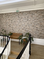 A staircase with a stone wall, a wooden bench, and a potted plant.