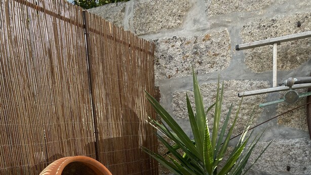 A garden with a bamboo fence, a terracotta pot, and a variety of pebbles. - GuestHouse do Marquês (Porto)