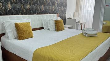 Ein Hotelzimmer mit einem großen Bett, einem Kopfteil, einem Nachttisch, einem Spiegel und einem Fenster mit Vorhängen.