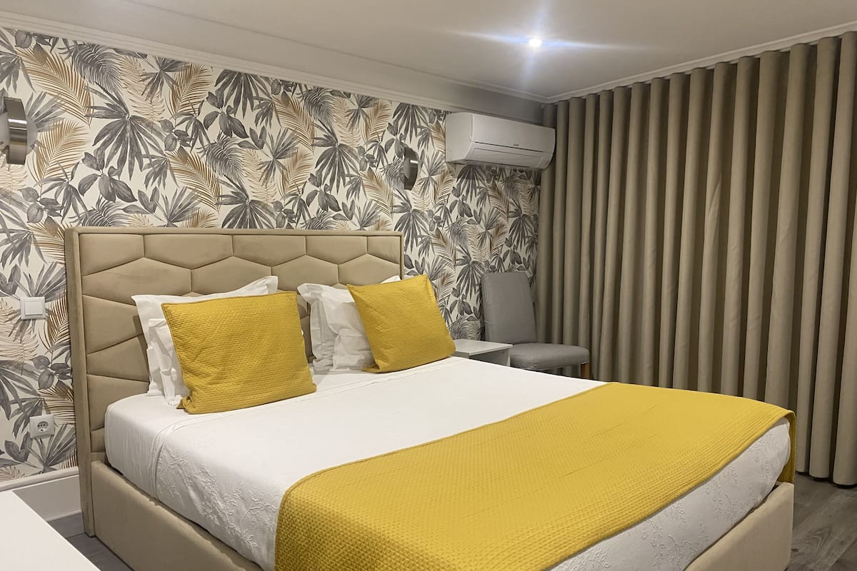 Una cama con cabecera, una mesita de noche y una silla.