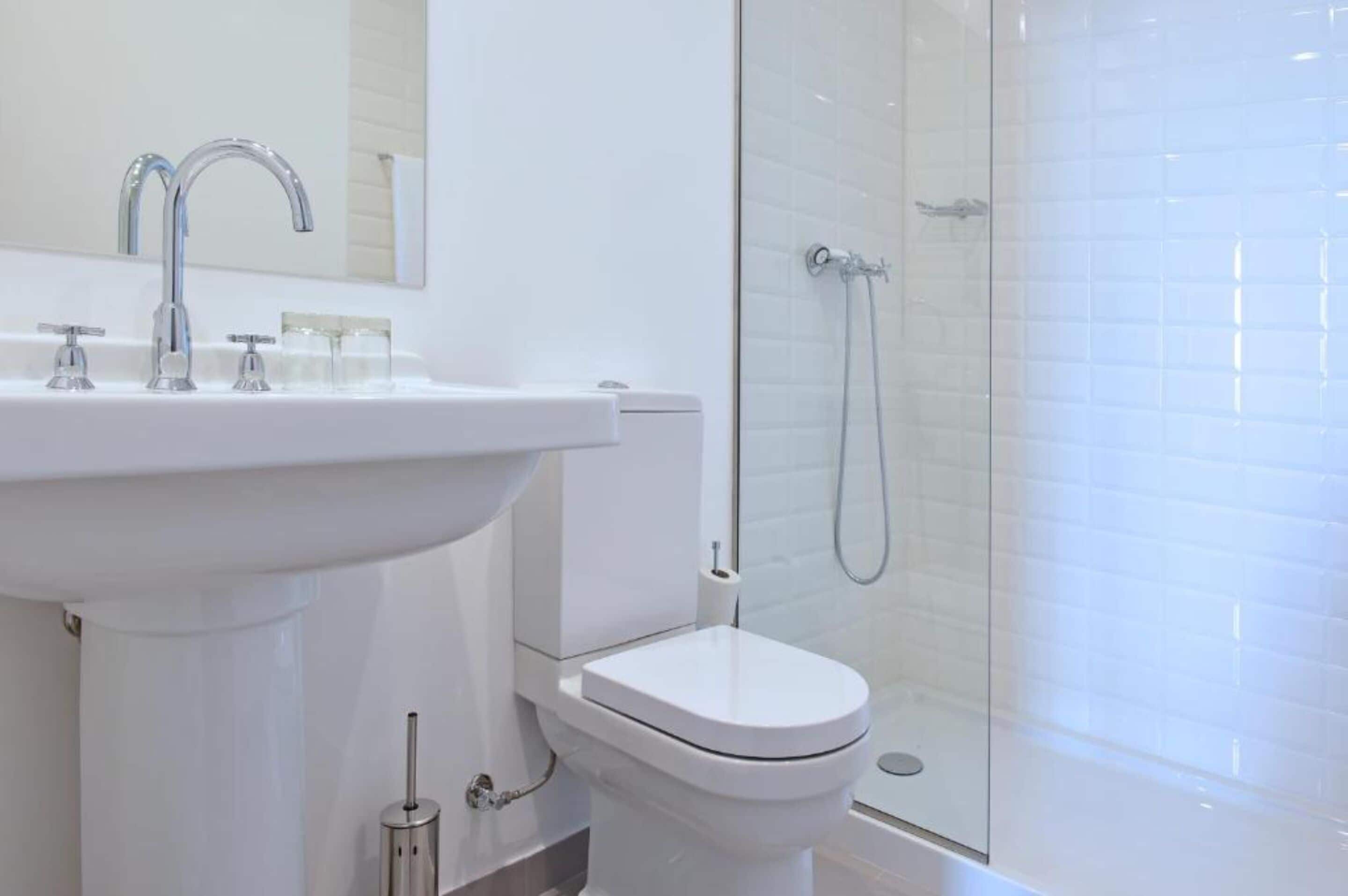 A modern bathroom with a white sink, a toilet, and a glass-enclosed shower.