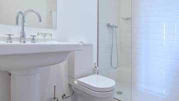 A modern bathroom with a white sink, a toilet, and a glass-enclosed shower.