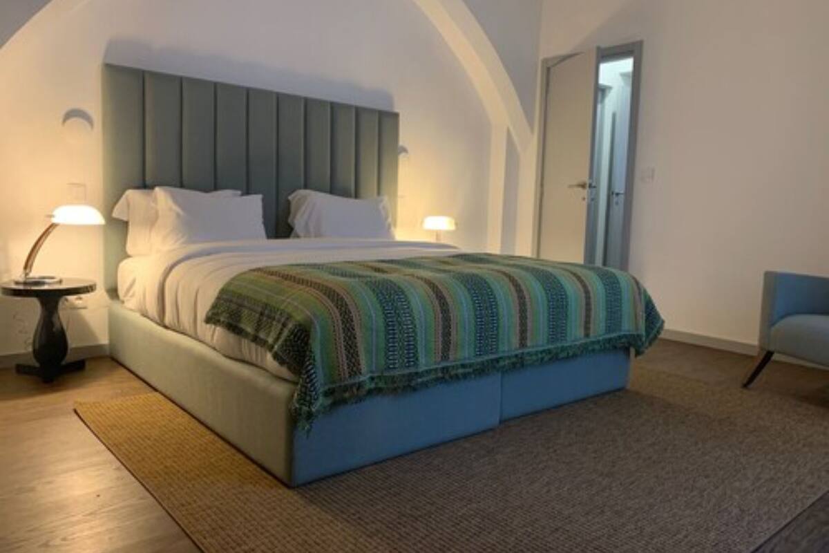A bedroom with a bed, bedside lamps, and a door.