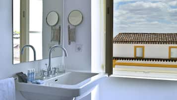 Un baño con lavamanos, dos espejos y una ventana con vistas a un edificio.