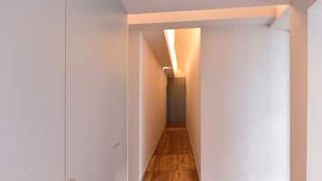 A narrow hallway with wooden flooring and white walls.