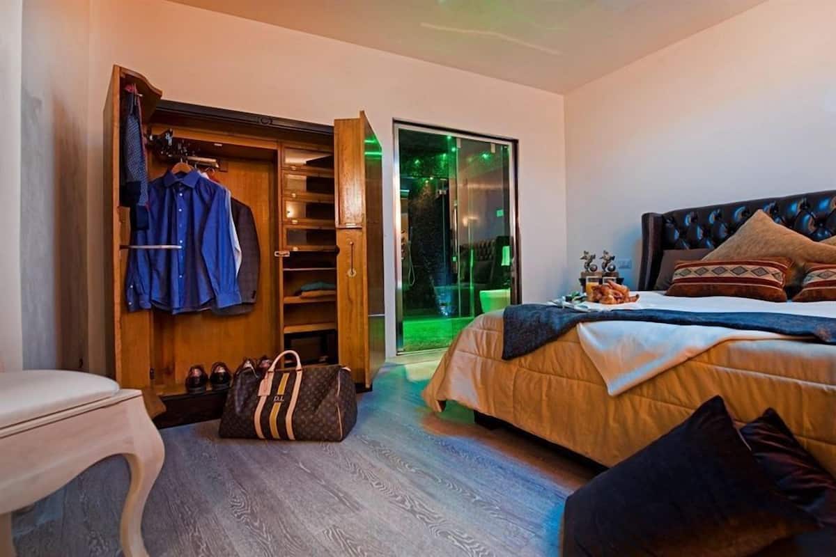 A bedroom with a bed, a wardrobe, a small table, and a chair.