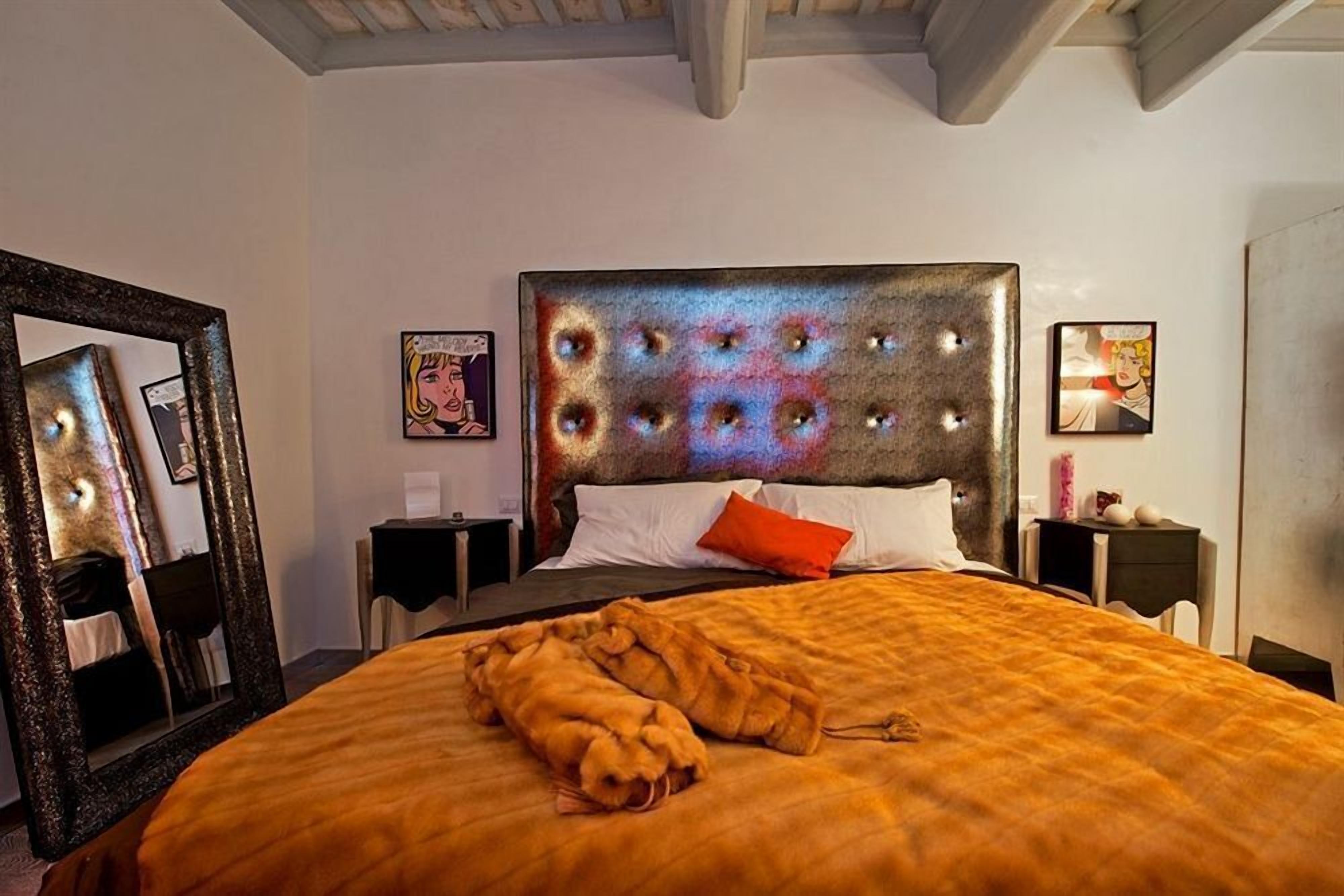 Een hotelkamer met een groot bed, een spiegel en kunstwerken aan de muur.