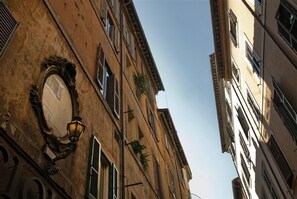 A tall building with multiple windows and a round, ornate clock on the facade. - Pantheon Relais (Rome)