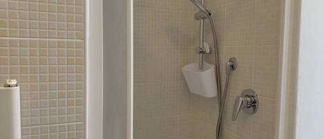 A shower with a handheld showerhead and a wall-mounted faucet.