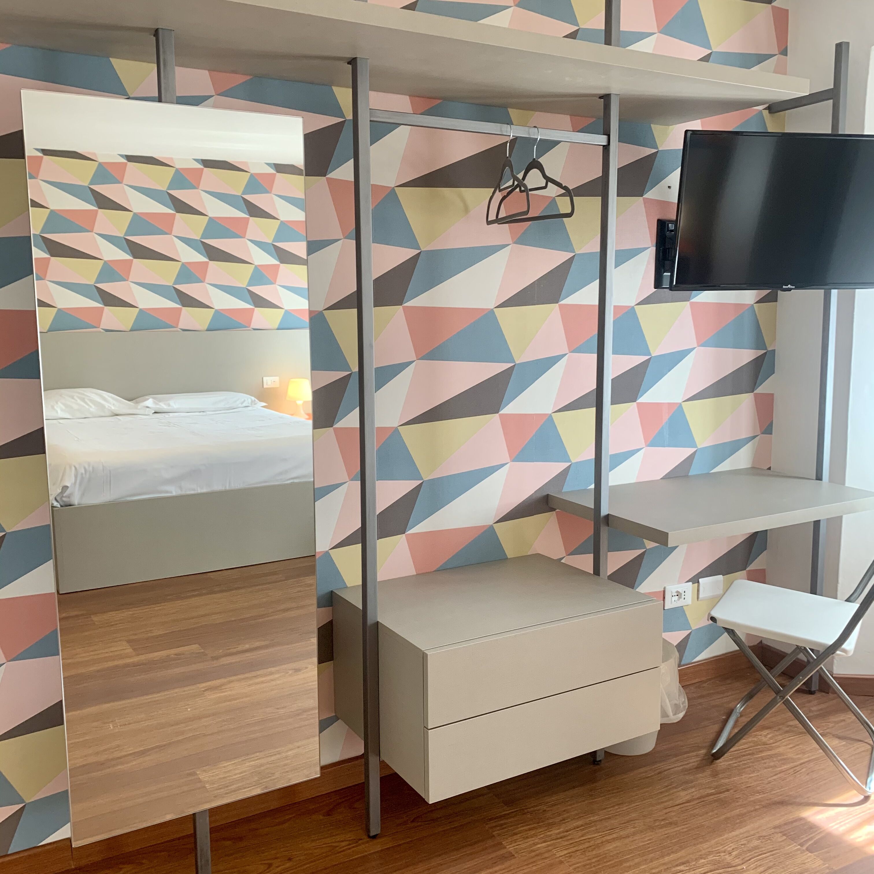 A room with a bed, a TV, a desk, and a chair.