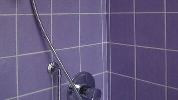 Une douche équipée d’un pommeau de douche à main et de commandes murales.