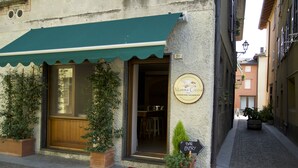 Una calle estrecha con un edificio que tiene un toldo verde y un letrero que anuncia la Academia de Cocina Mama Ciccia's.