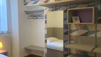 Una camera del dormitorio con un letto a castello, una scrivania, una sedia, una finestra con tende e una parete con motivo geometrico.