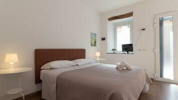 A neatly arranged bedroom with a bed, bedside lamps, a small table, and a window with a view.