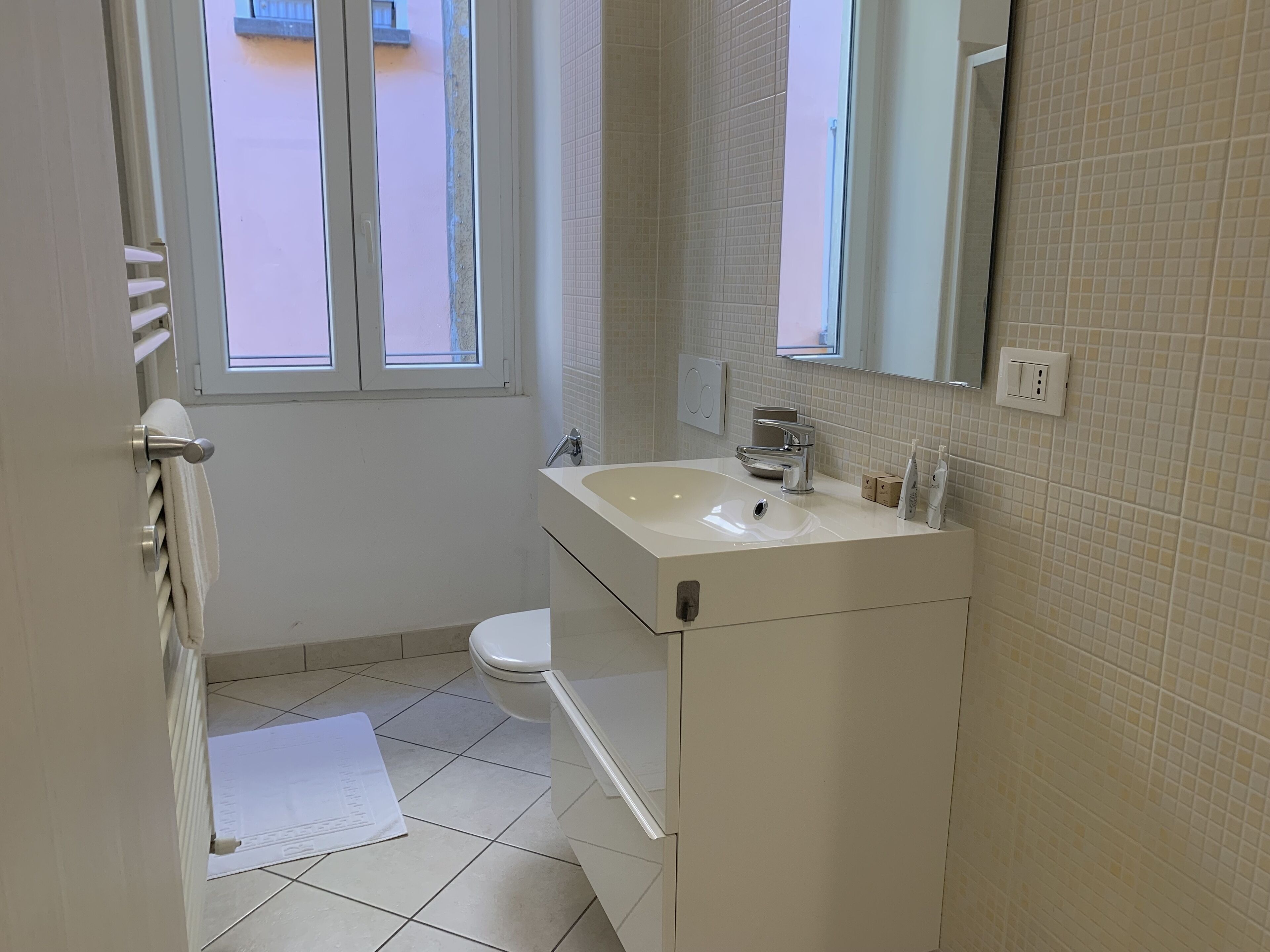 Un baño pequeño y limpio con un lavamanos blanco, un espejo y un inodoro.