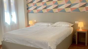 Ein ordentlich bezogenes Bett in einem Raum mit einer Wand mit geometrischem Muster darüber.