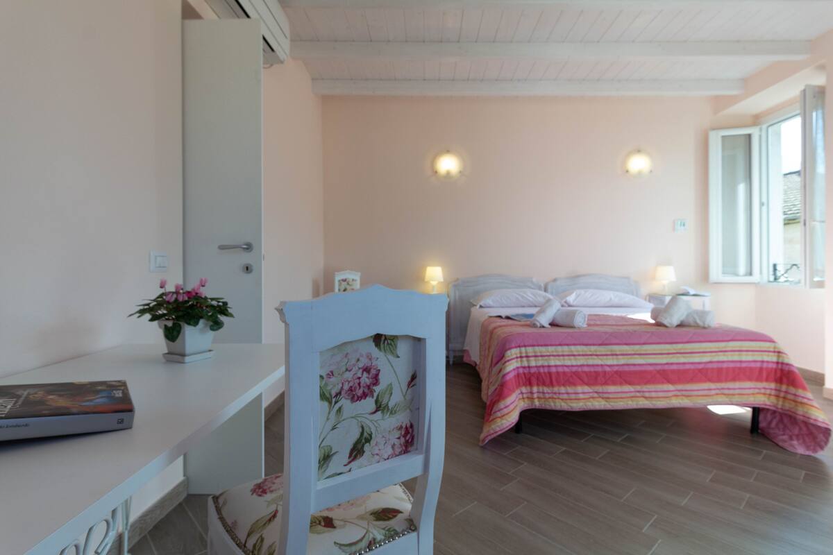 Une chambre à coucher avec un lit, des tables de chevet, une chaise, un bureau et une fenêtre.