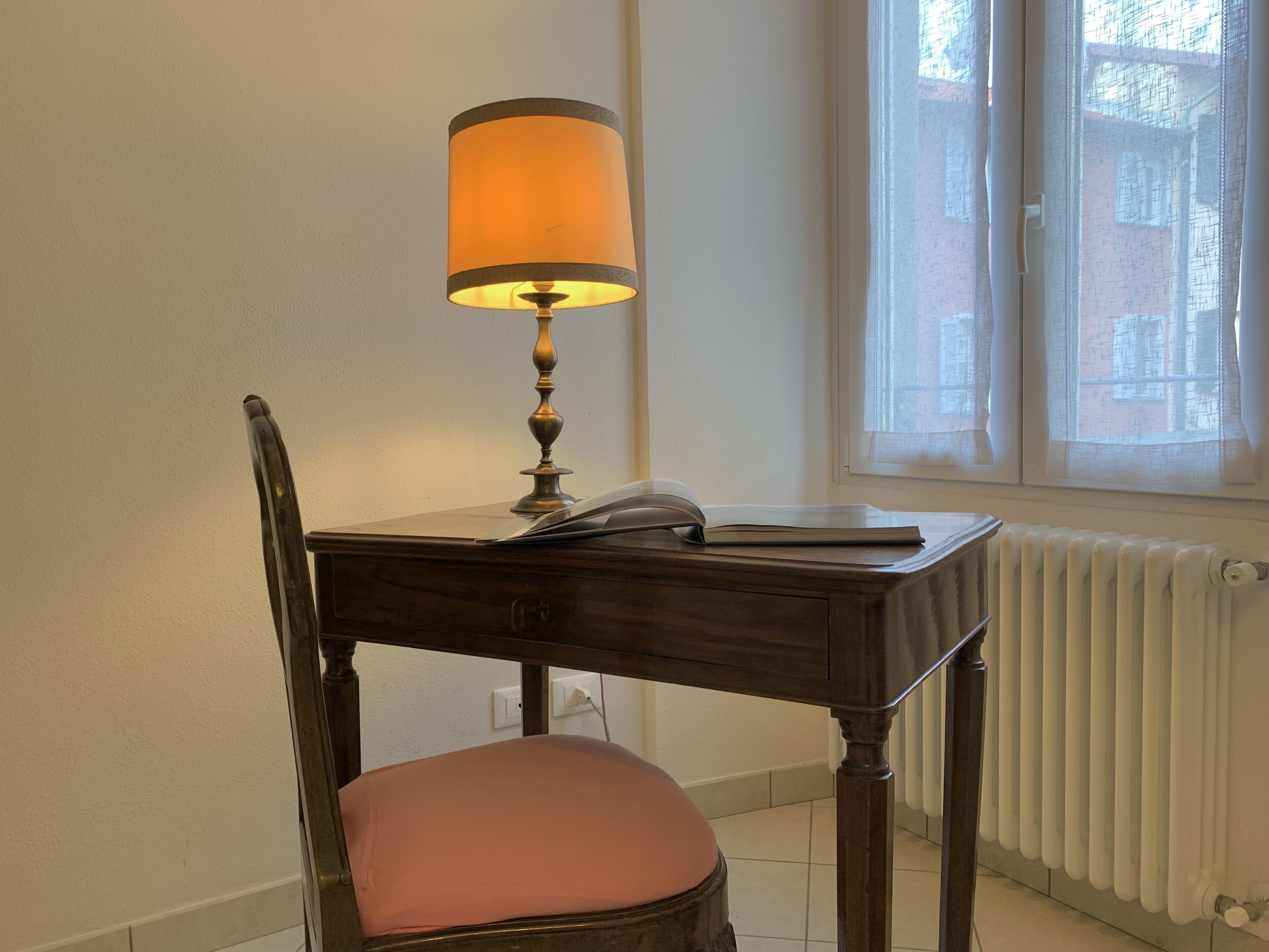 A wooden desk with a lamp, a chair, and a radiator.