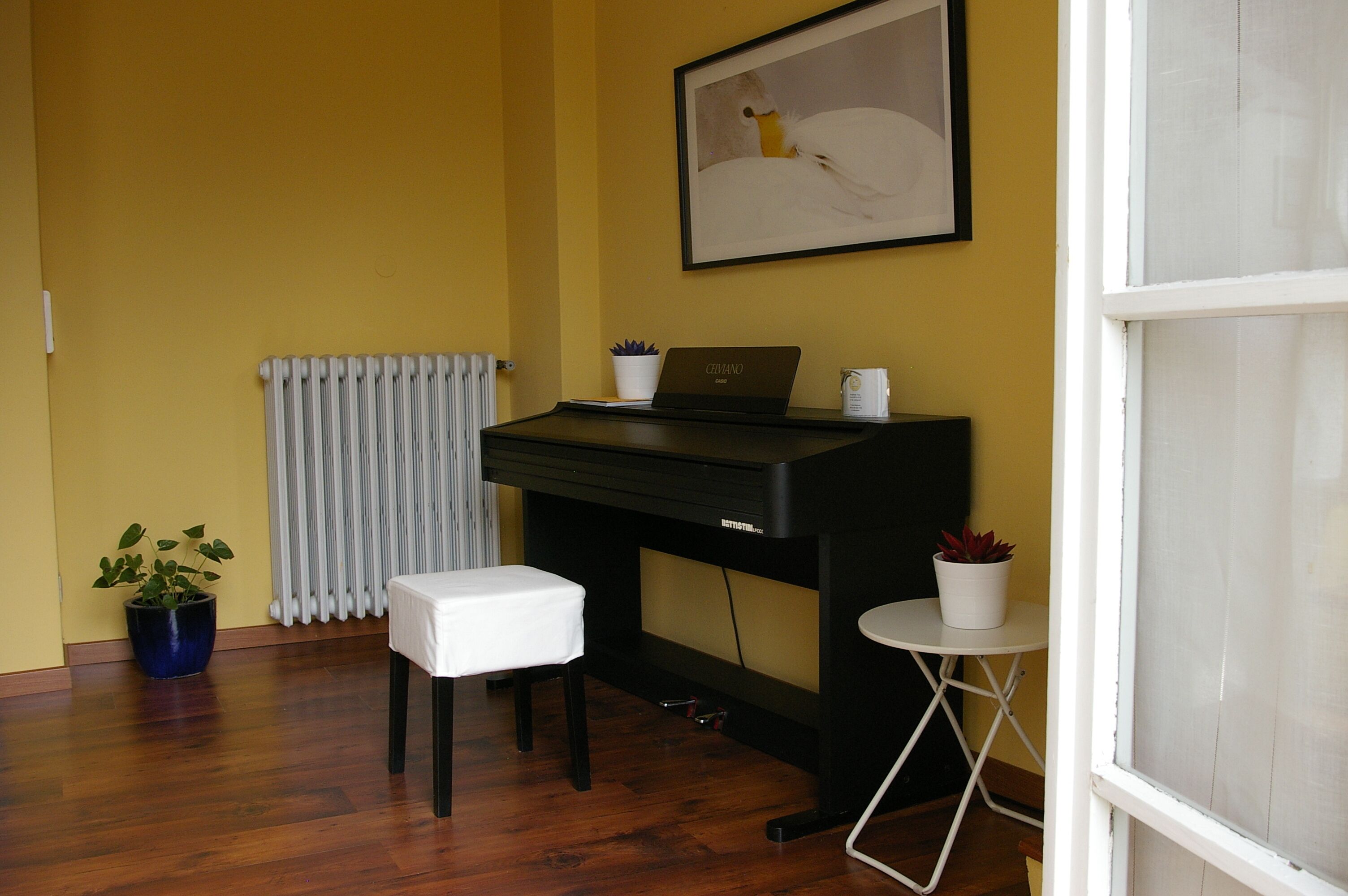 A room with a black desk, a white chair, a small table, and a potted plant.