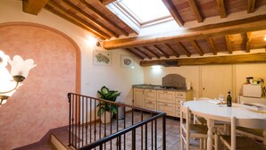 A kitchen with wooden beams, a skylight, a dining table, and a staircase. - Donna Nobile (San Gimignano)