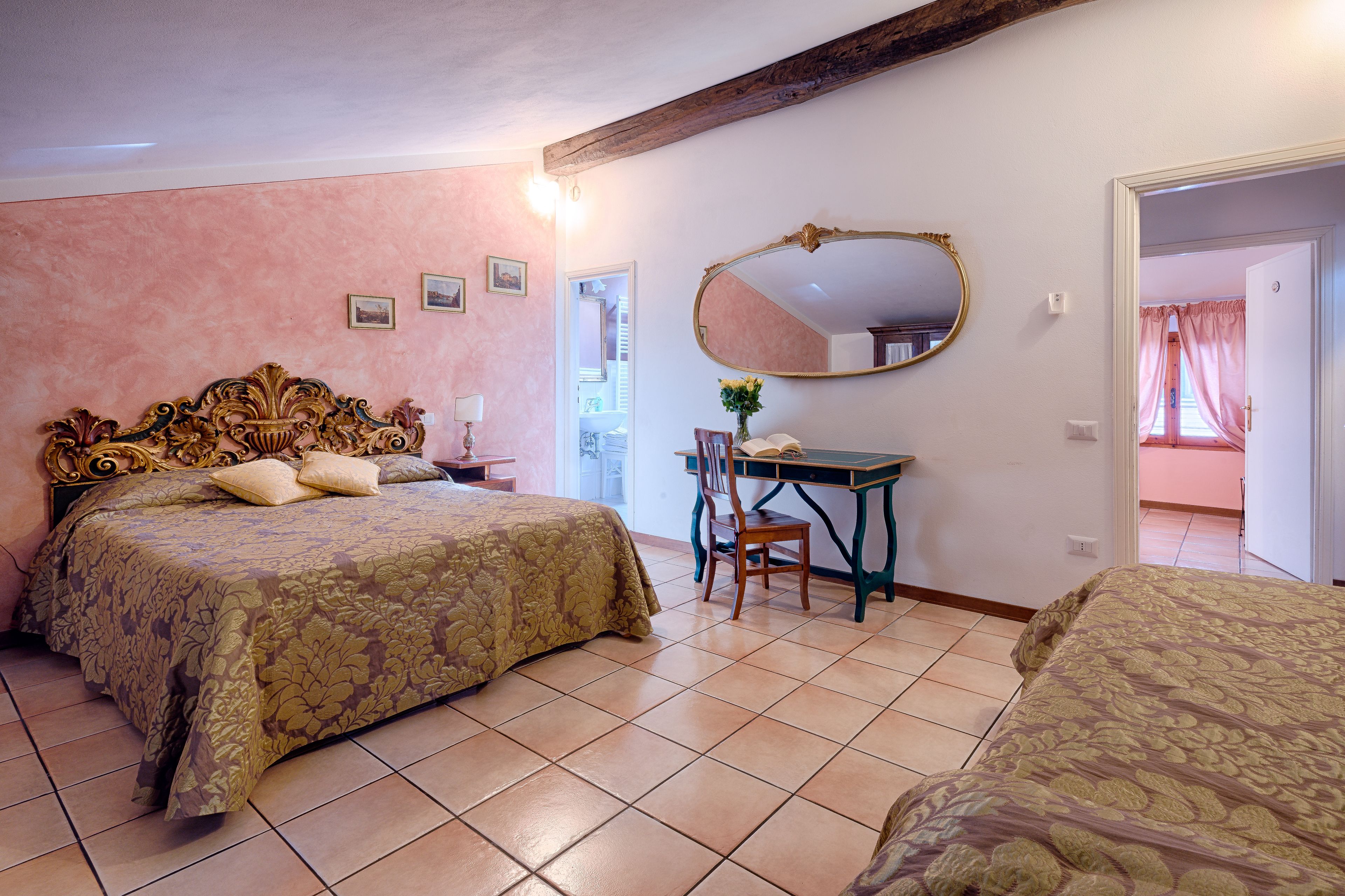 A bedroom with a large bed, a desk, and a mirror.