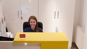 Una reception con un motivo giallo, una sveglia digitale e un cartello con su scritto 'ATC'.