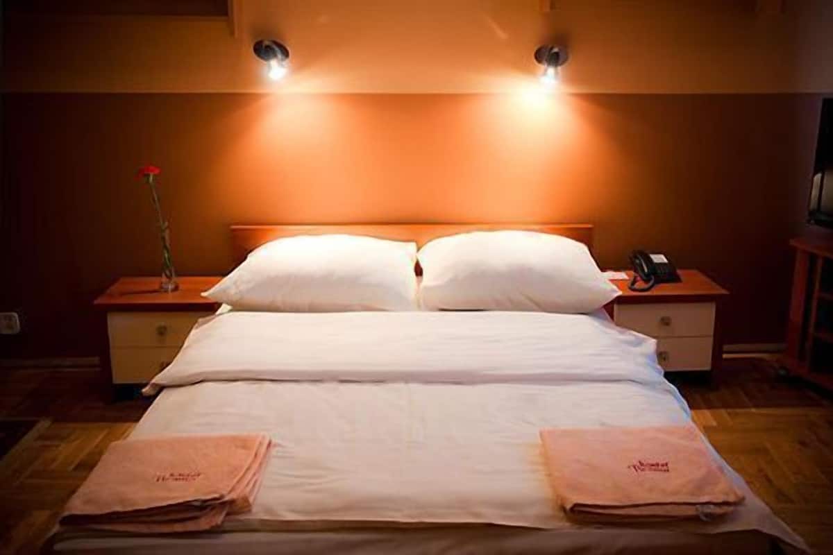 A hotel room with a bed, two bedside tables, and a nightstand.