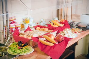 Een buffet met diverse etenswaren, zoals brood, fruit en zuivelproducten.