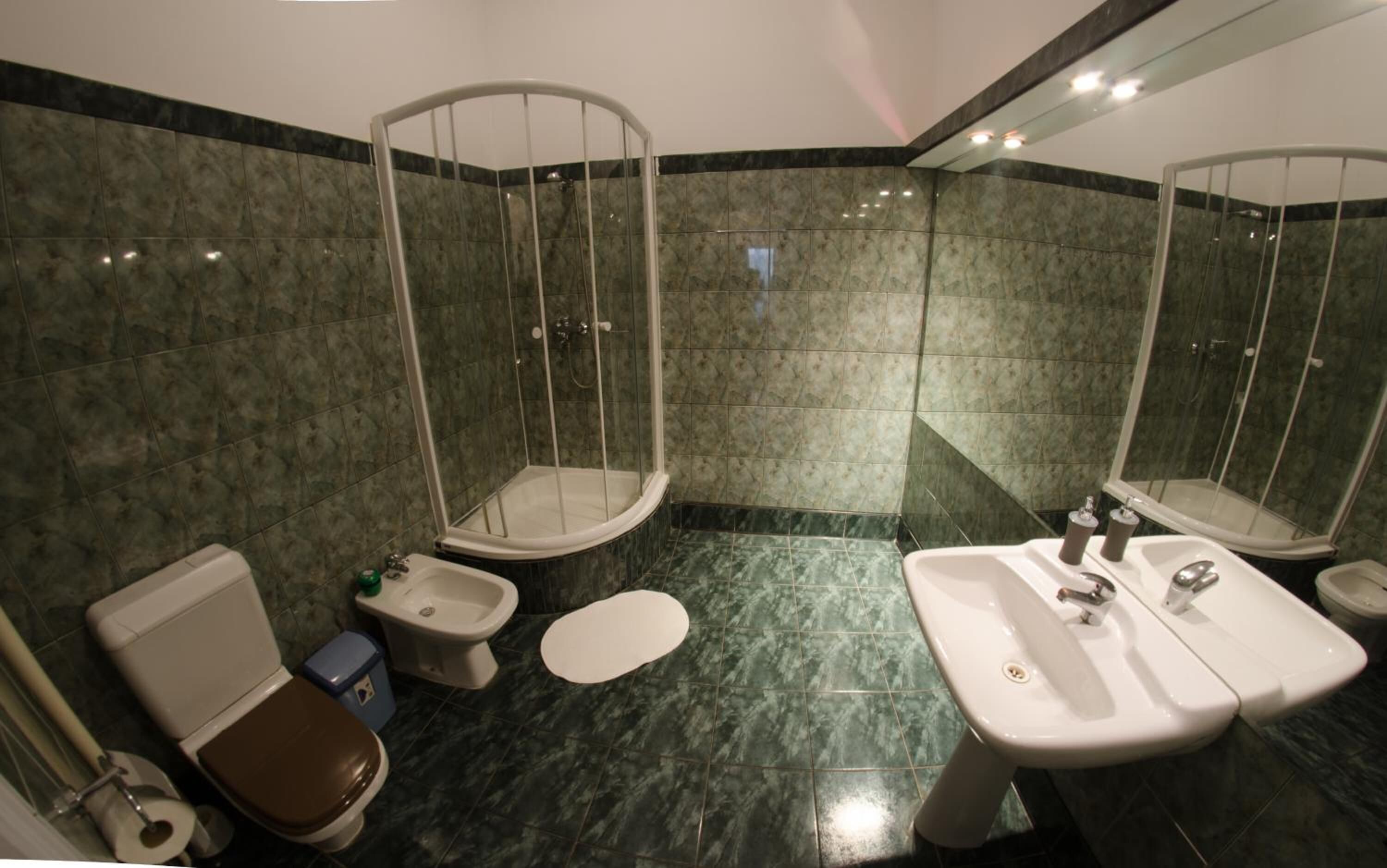 A bathroom with a toilet, bidet, and shower enclosure.
