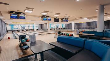 A bowling alley with multiple lanes, seating areas, and overhead scoreboards.