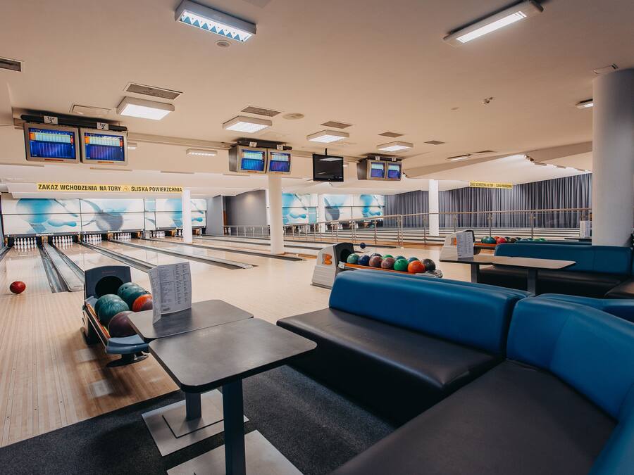 A bowling alley with multiple lanes, seating areas, and overhead scoreboards.
