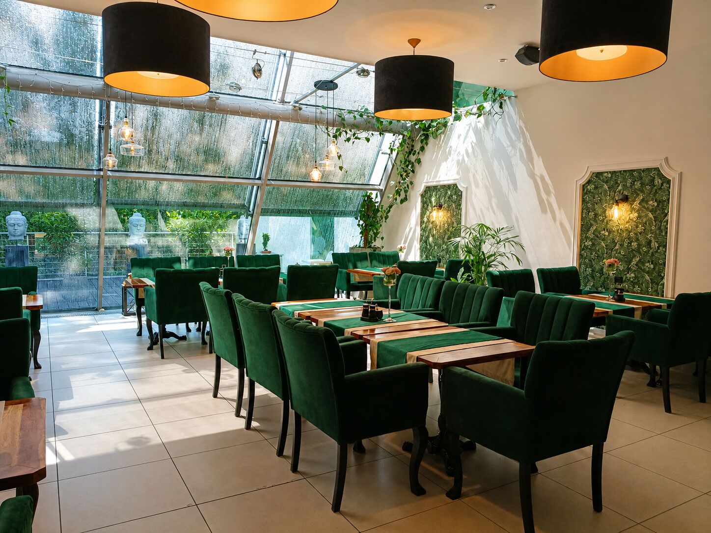 A restaurant with green upholstered chairs, wooden tables, and hanging pendant lights.