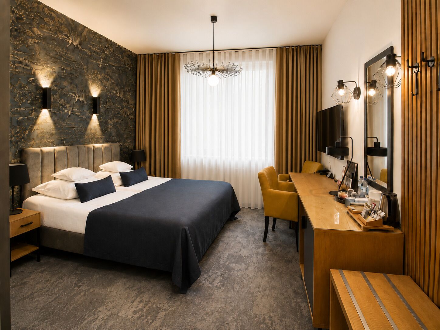A modern hotel room with a large bed, a desk, a chair, a mirror, and a decorative wall.
