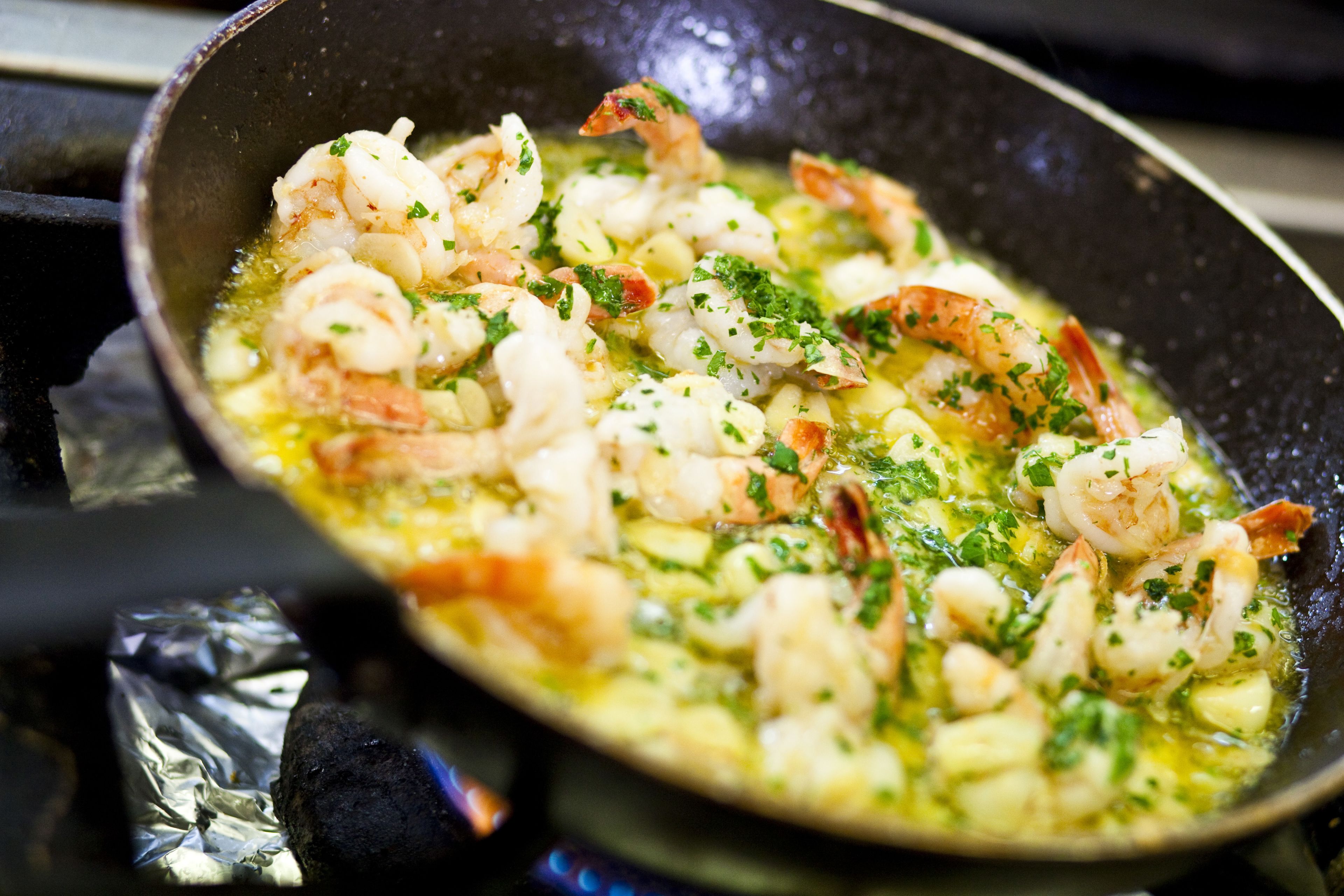 Una sartén con camarones cocinándose en salsa.