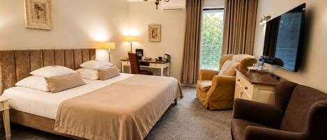 A hotel room with a large bed, a desk with a chair, a television, and a window with curtains.