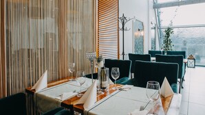 Un restaurante con pared de listones de madera, sillas tapizadas de verde y una mesa preparada para comer.