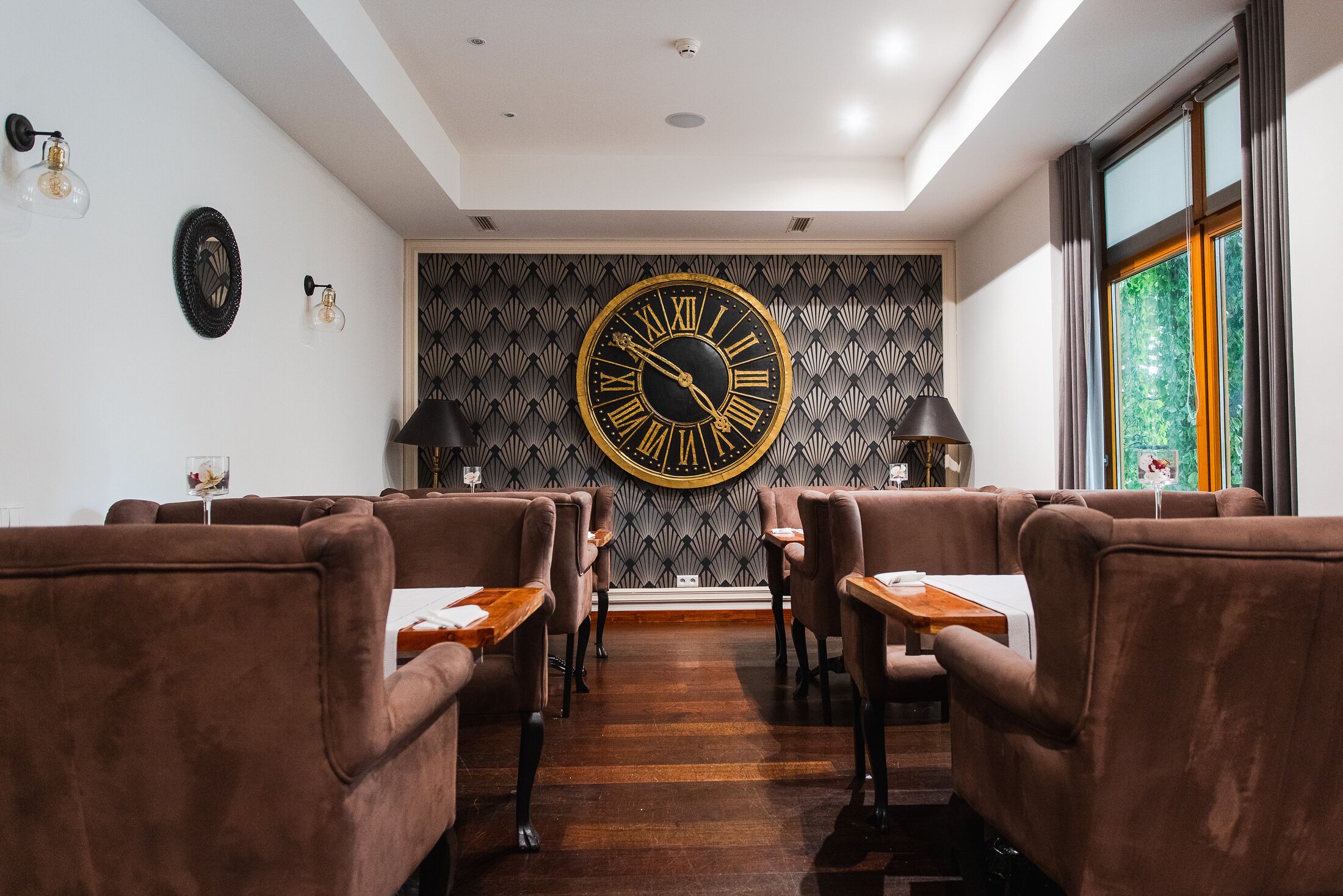 Un interior moderno con sofás de cuero marrón, mesas de madera y un gran reloj de pared.