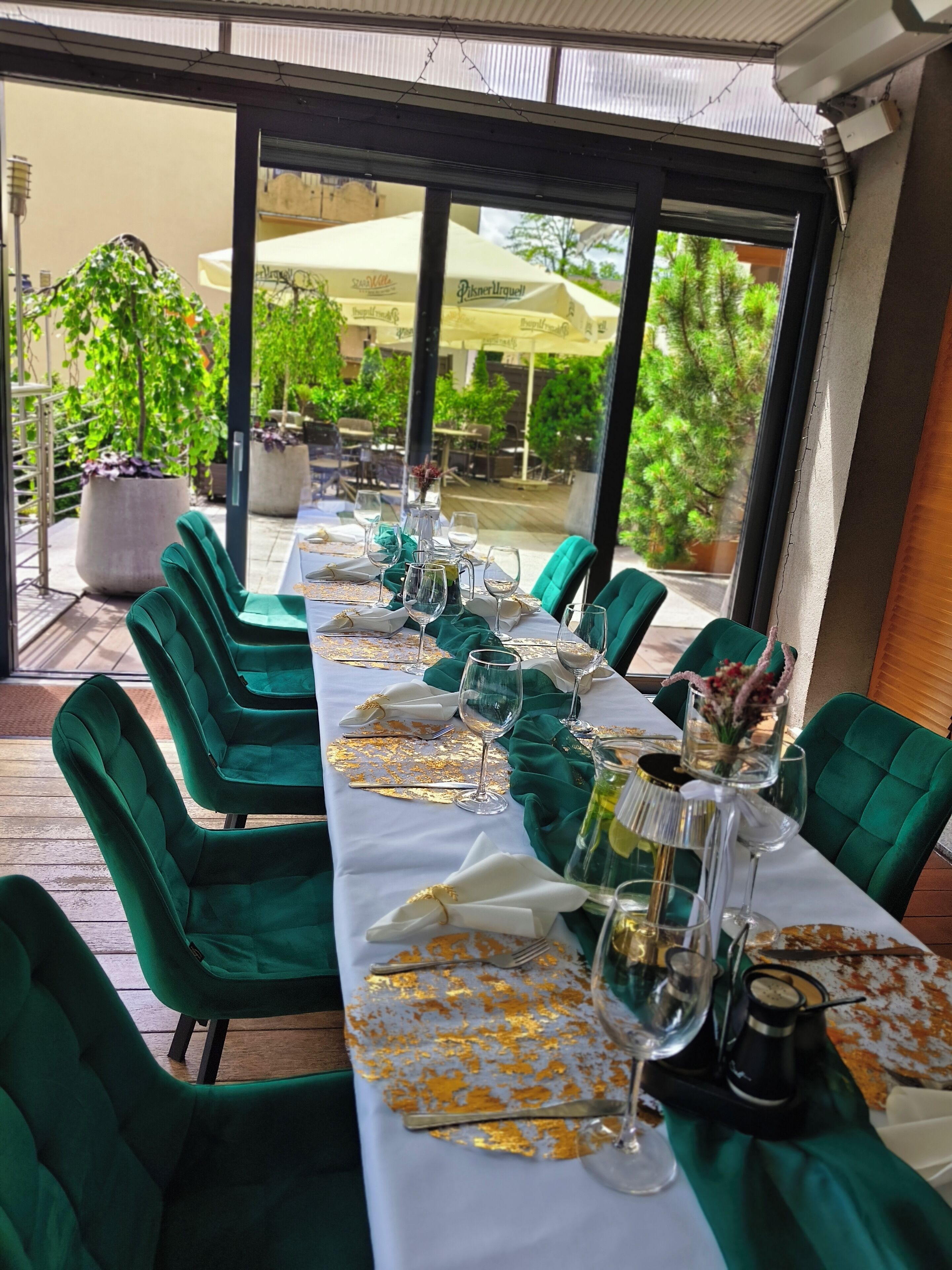 Comedor con una mesa dispuesta para seis personas, sillas tapizadas en verde y vistas del patio exterior.