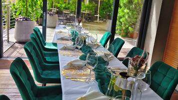 Comedor con una mesa dispuesta para seis personas, sillas tapizadas en verde y vistas del patio exterior.