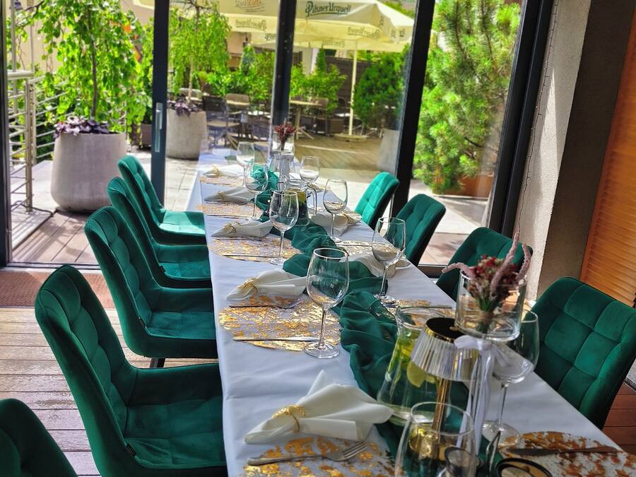 Comedor con una mesa dispuesta para seis personas, sillas tapizadas en verde y vistas del patio exterior.