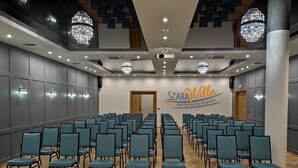 Un salón de conferencias con filas de sillas color turquesa, suelo de madera y candelabros.