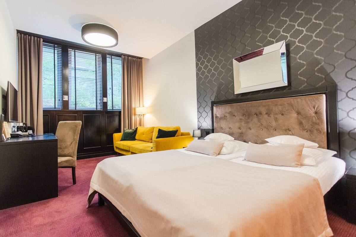 Habitación de hotel con una cama grande, un escritorio, una silla y un sofá.
