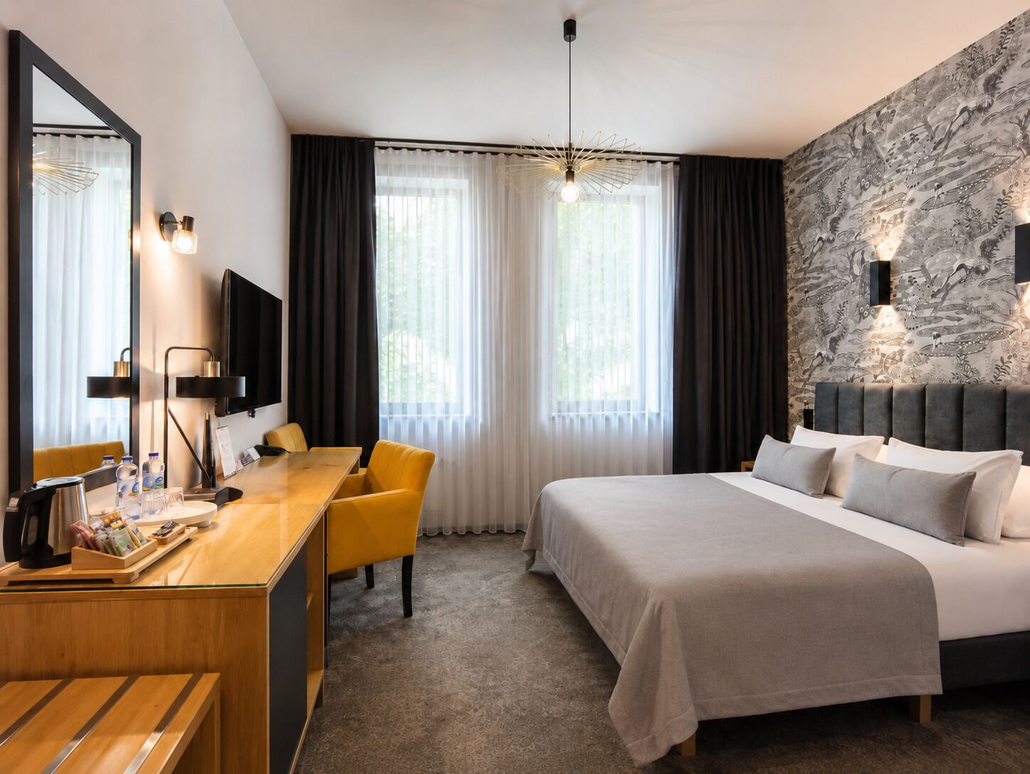 A modern hotel room with a bed, a desk, a chair, a television, and a large window with curtains.